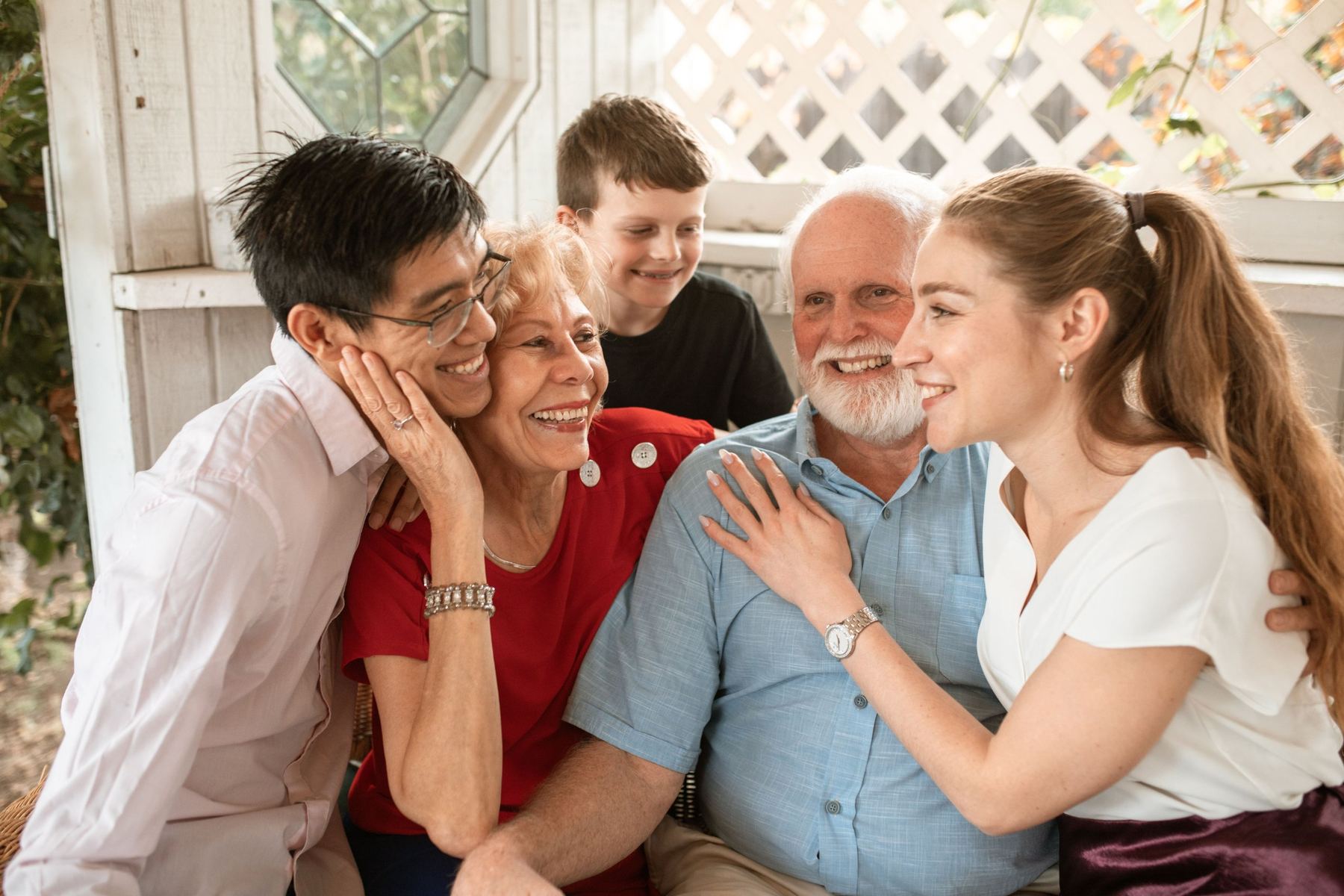 Three generations of a family laughing together on a garden porch