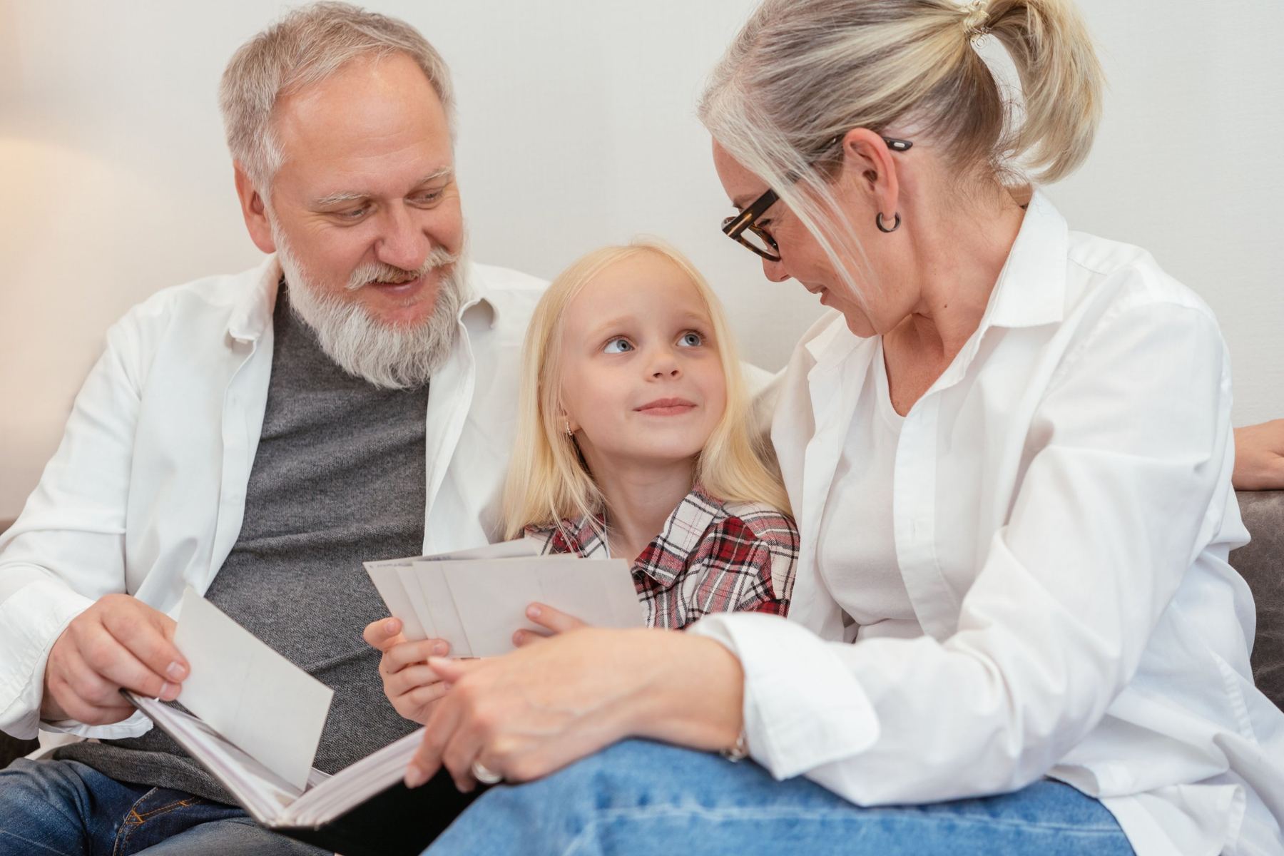 Grandparents looking through a family photo album with their granddaughter