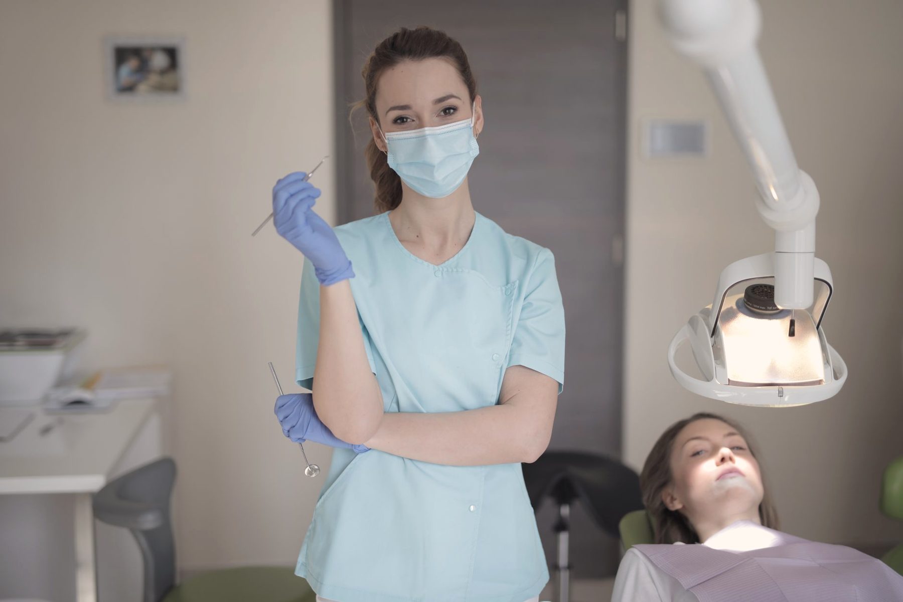 A dental hygienist standing beside a patient in a bright treatment room